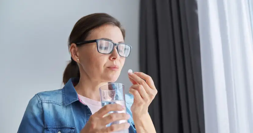 Kobieta w okularach bierze tabletkę, zastanawiając się nad mysimba skutki uboczne.