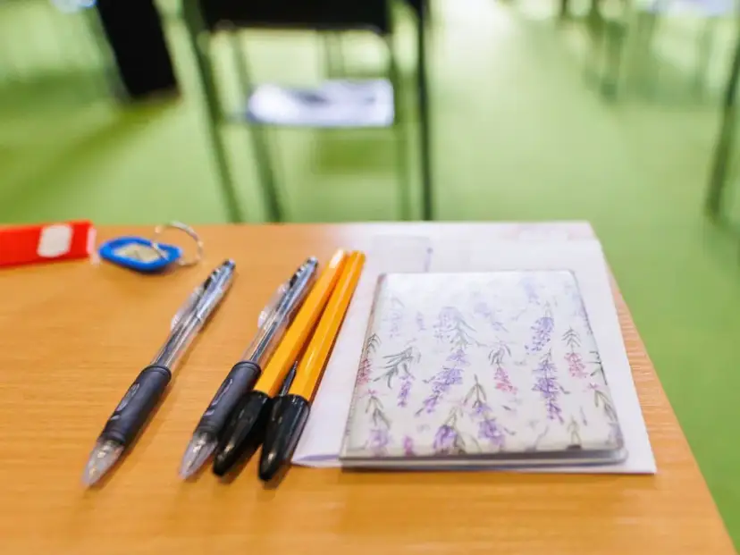 Długopisy i notes z lawendą na drewnianym biurku.