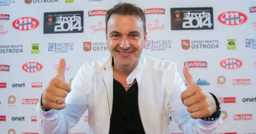 Uśmiechnięty mężczyzna w białej kurtce daje kciuki w górę. Czy to on śpiewa, a ona tańczy dla niego?