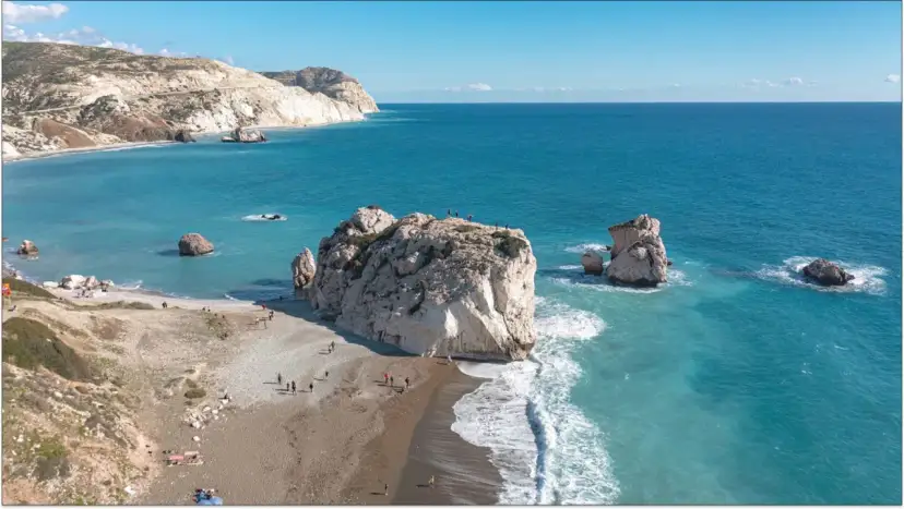Skały Afrodyty na Cyprze. Czy jest bezpiecznie? Turyści spacerują po plaży, podziwiając lazurowe morze i formacje skalne.