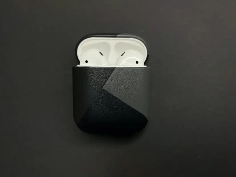 AirPods in einer schwarzen Hülle mit grauem geometrischem Muster.