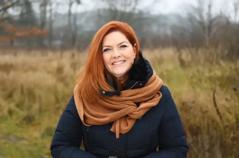 Uśmiechnięta Kasia w rudych włosach, otulona szalikiem, cieszy się listopadowym dniem.