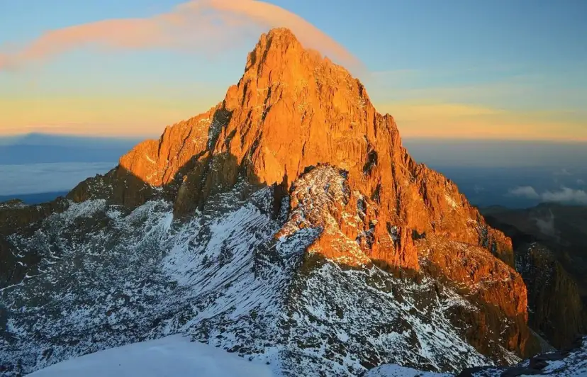 Ośnieżone zbocza i skaliste szczyty Mount Kenya w złotym blasku wschodu słońca.