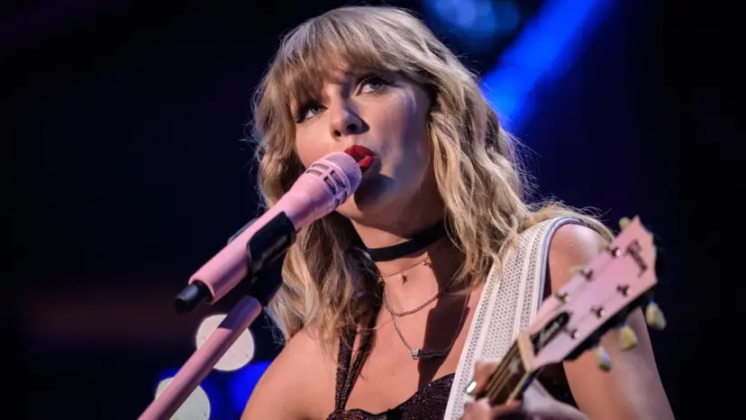 Taylor Swift śpiewa do różowego mikrofonu, grając na gitarze. To scena z jej epickiej trasy "reputation stadium tour", która na zawsze zmieniła jej wizerunek.