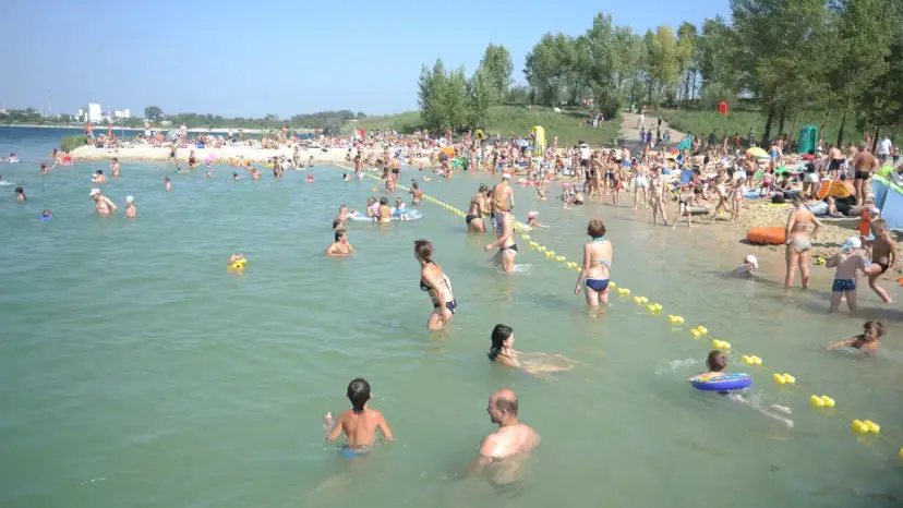 Tłum ludzi na plaży i w wodzie, idealne miejsce na wakacje z bonem turystycznym.