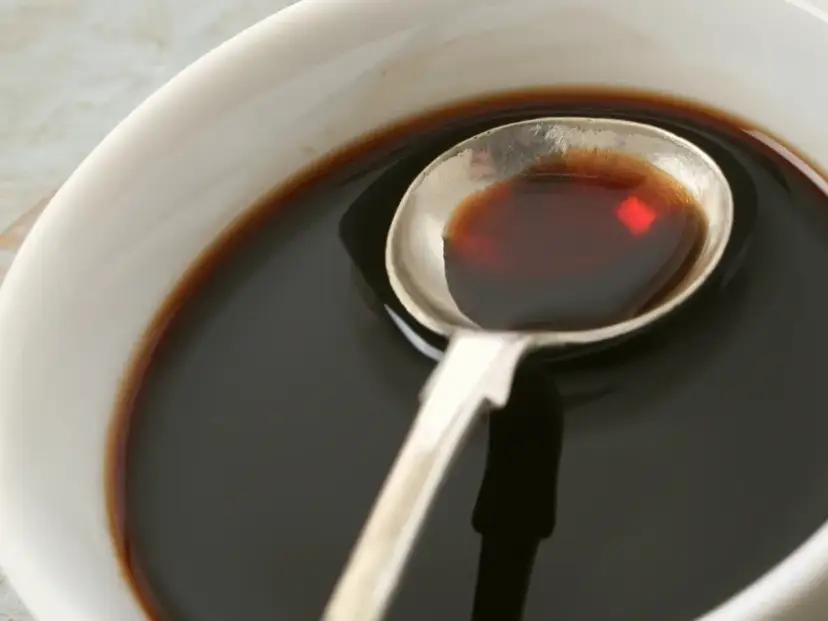 Łyżka z ciemnym płynem, idealnym do sosów i dressingów. Inspiracja do ocet balsamiczny przepisy.