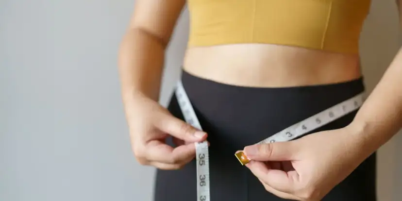 Kobieta mierzy talię centymetrem. Dowiedz się, jak podkręcić metabolizm po 40. i odzyskać formę.
