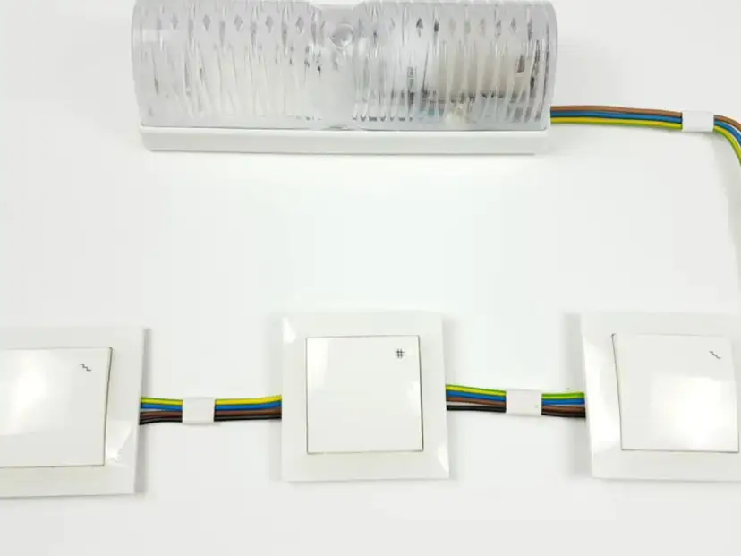 Schemat instalacji elektrycznej: jak podłączyć łącznik krzyżowy. Widoczne trzy łączniki i lampa.