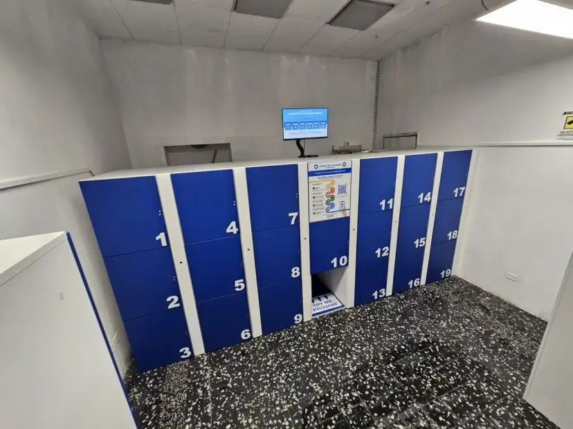 Blue and white numbered luggage lockers with a digital screen and instructions.