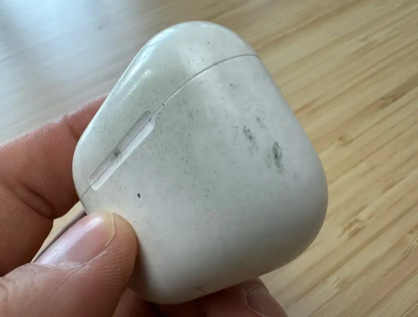 Eine schmutzige weiße Hülle für AirPods wird von einer Hand gehalten.