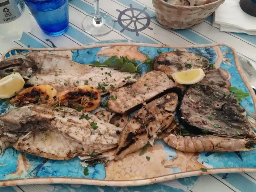 A platter of grilled fish and shrimp garnished with lemon and parsley.