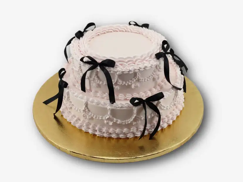 Dwupiętrowy tort w kolorze pudrowego różu, ozdobiony czarnymi wstążkami. Idealny na osiemnastkę, zastanawiasz się, ile kosztuje catering na 18?
