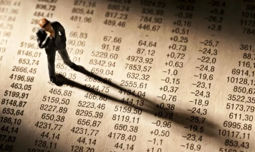 Figurka biznesmena pochyla się nad tabelą finansową, sugerując zmartwienie nowym podatkiem od lokat.