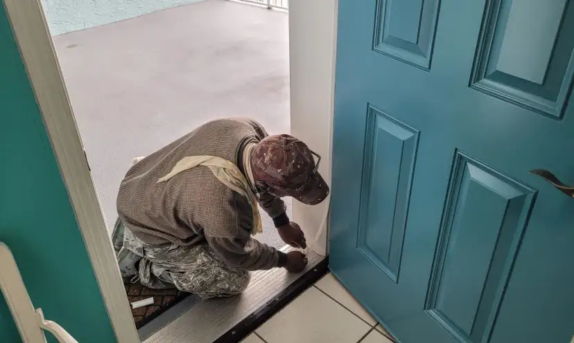 Pracownik montuje uszczelkę, co jest ważnym elementem uzasadnienia wymiany drzwi wejściowych na nowe, zapewniające lepszą izolację.