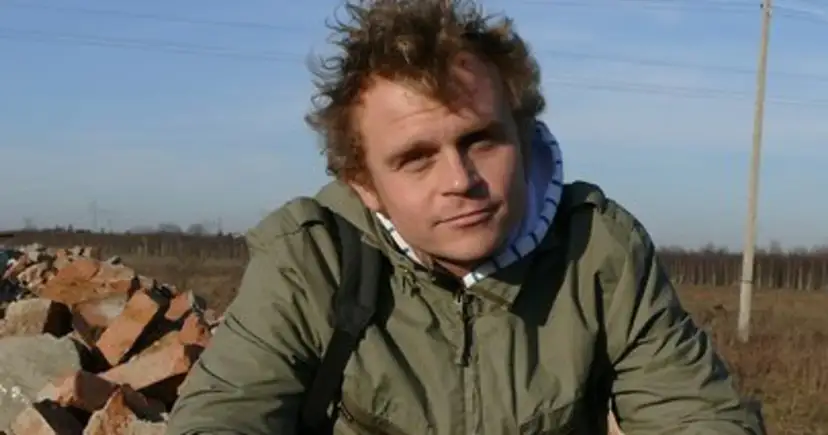 Piotr Rogucki, w otoczeniu gruzu, z charakterystyczną fryzurą, jakby inspirowany swoimi utworami.