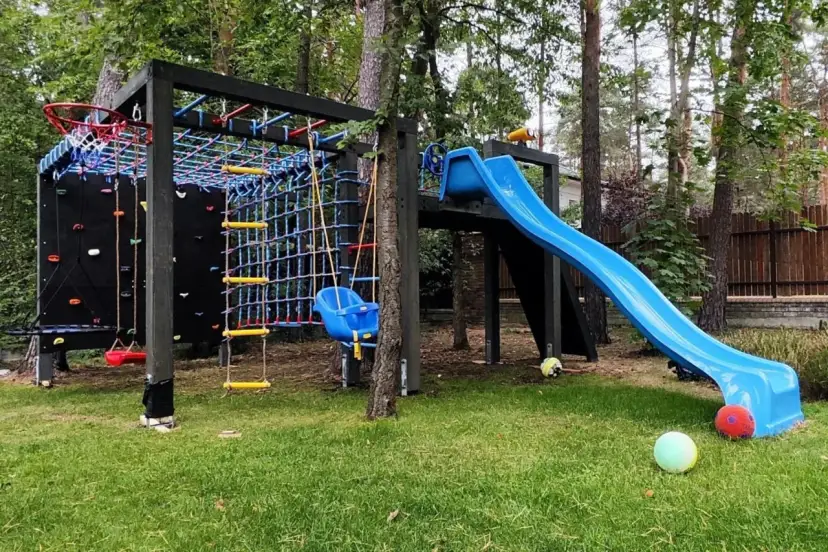 Plac zabaw z drabinką, zjeżdżalnią, huśtawką i ścianką wspinaczkową.