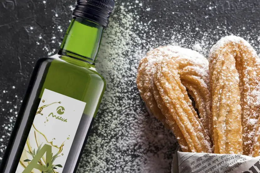 Botella de aceite de oliva junto a churros espolvoreados con azúcar glas.