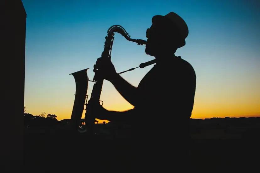 Sylwetka muzyka w kapeluszu grającego na saksofonie o zachodzie słońca. Prawdziwy mistrz, jeden z najlepszych bluesmanów świata.