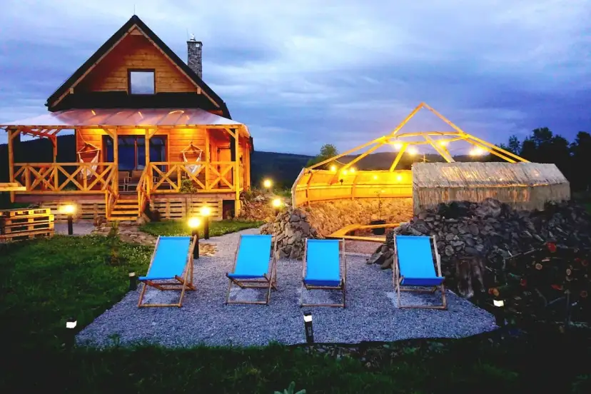 Drewniany domek z werandą, jacuzzi pod zadaszeniem i leżakami w malowniczej okolicy.