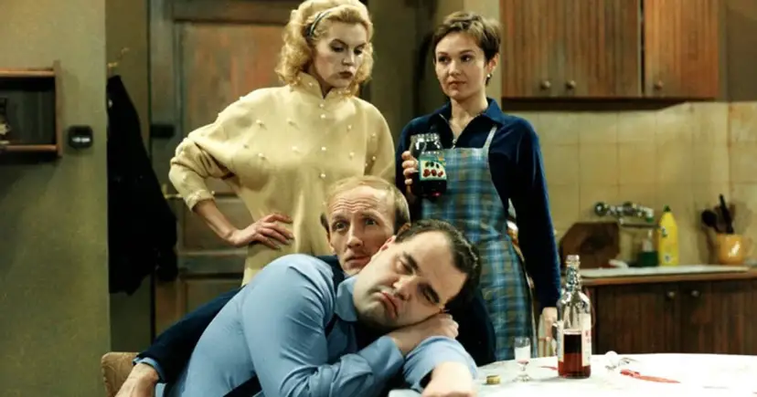 Tadeusz Norek, pijany, opiera się o kolegę. Dwie kobiety patrzą na nich z dezaprobatą.