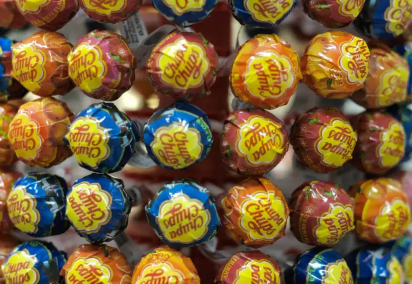 Zbliżenie na kolorowe lizaki Chupa Chups w opakowaniach z owocowymi wzorami.