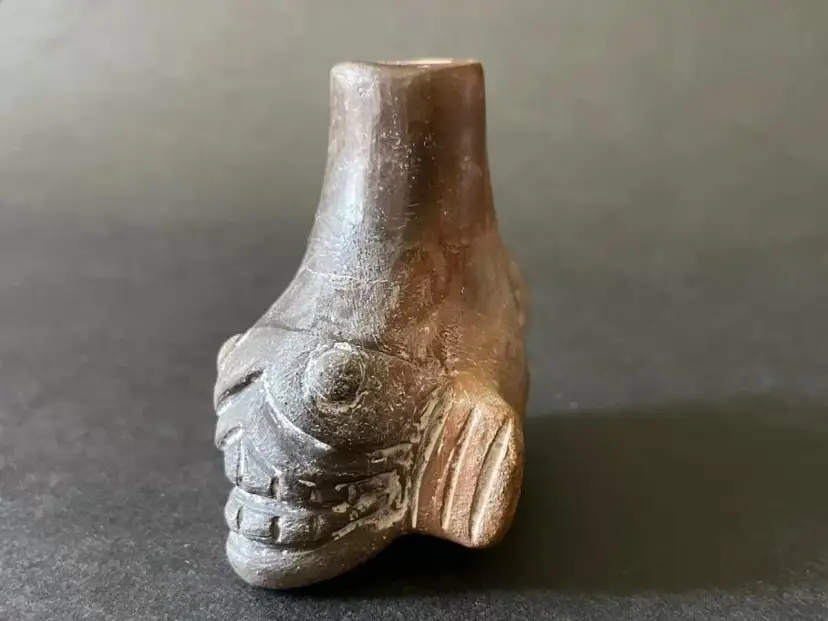 Mroczny aztecki gwizdek śmierci w kształcie ryby, z wyrazistymi oczami i zębami, wydaje przerażający dźwięk.