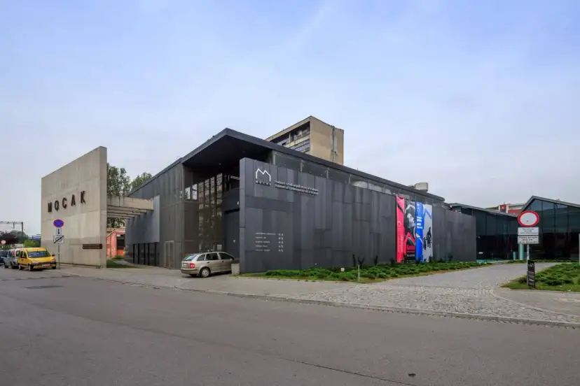 Nowoczesny budynek MOCAK Muzeum Sztuki Współczesnej w Krakowie z betonowym napisem i szarymi panelami.