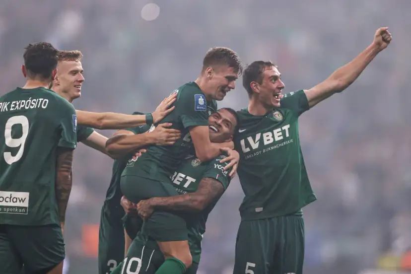 Piłkarze w zielonych koszulkach świętują zwycięstwo. Jeden z nich, z podniesioną ręką, krzyczy z radości. To oni pokazali ekstraklasę!