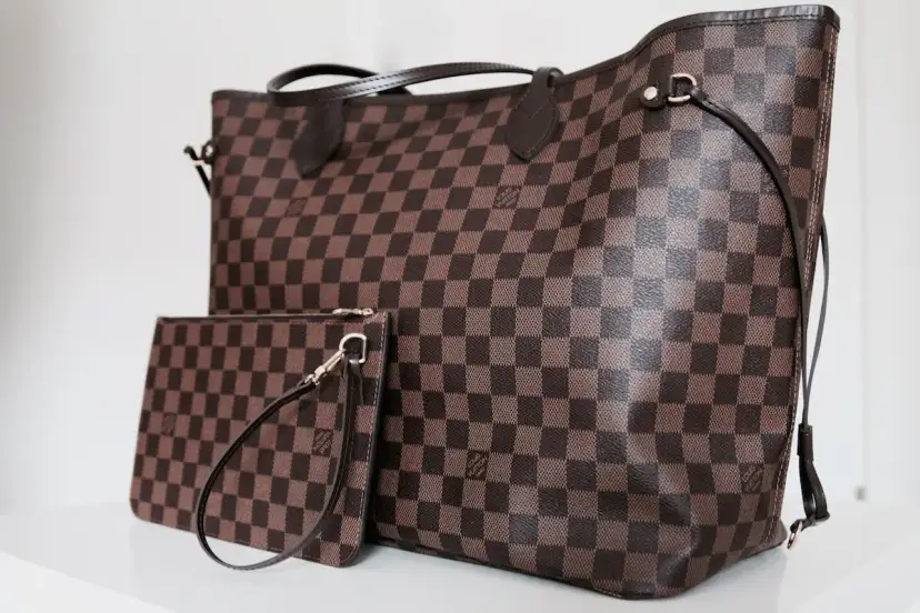 Duża torebka Louis Vuitton w kratkę, obok mniejsza kosmetyczka. Klasyczny wzór Damier Ebene.