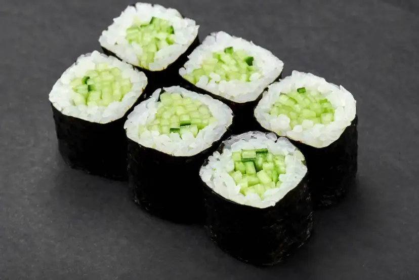 Sześć kawałków sushi z ogórkiem, ułożonych na ciemnym tle.