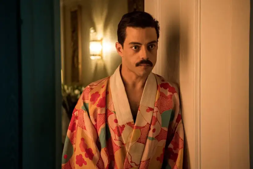Freddie Mercury w barwnym szlafroku, jakby zrodzony z **bohemian rhapsody**, opiera się o drzwi.