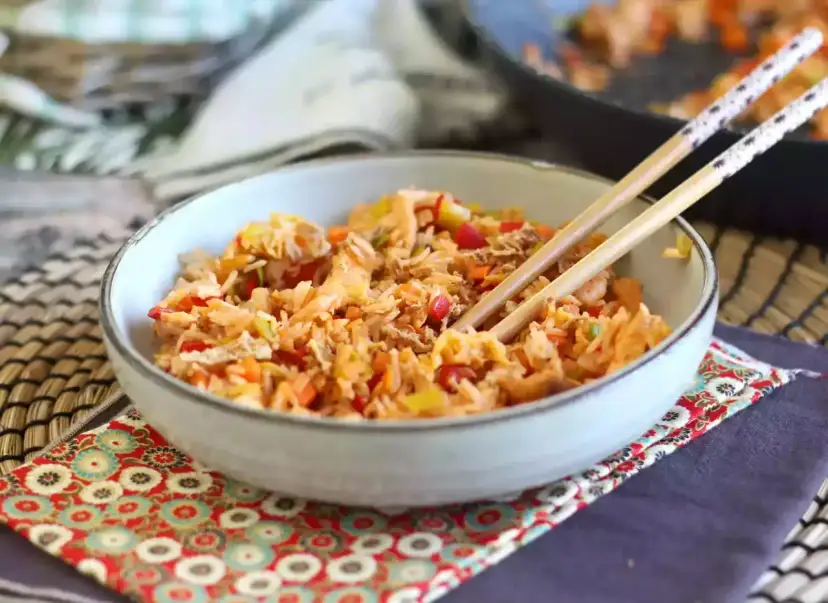 Miseczka pełna aromatycznego nasi goreng z warzywami i kawałkami mięsa, gotowa do jedzenia pałeczkami.