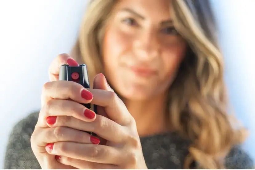 Kobieta z pomalowanymi na czerwono paznokciami trzyma gaz pieprzowy.