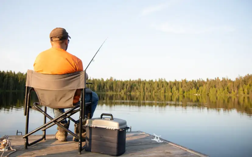 Wędkarz na pomoście, zastanawia się, ile kosztuje wyrobienie karty rybackiej.