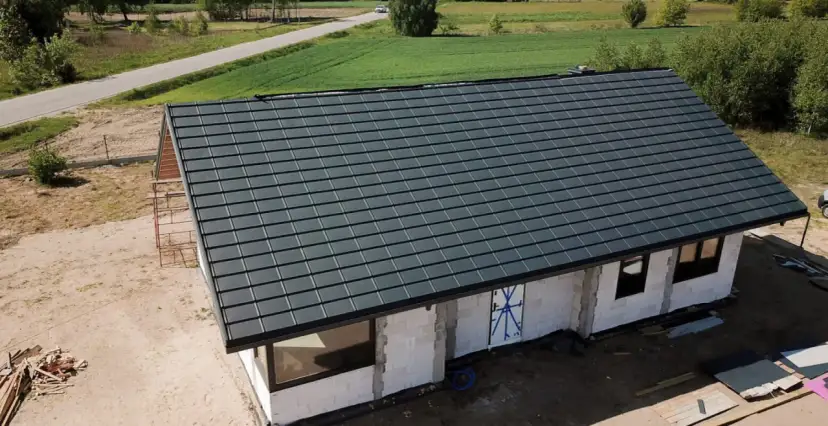 Nowy dom w budowie z ciemnoszarym dachem, widok z góry.