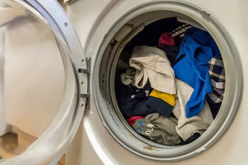 Otwarta pralka z wsadzonym praniem, w tym kolorowymi ubraniami.