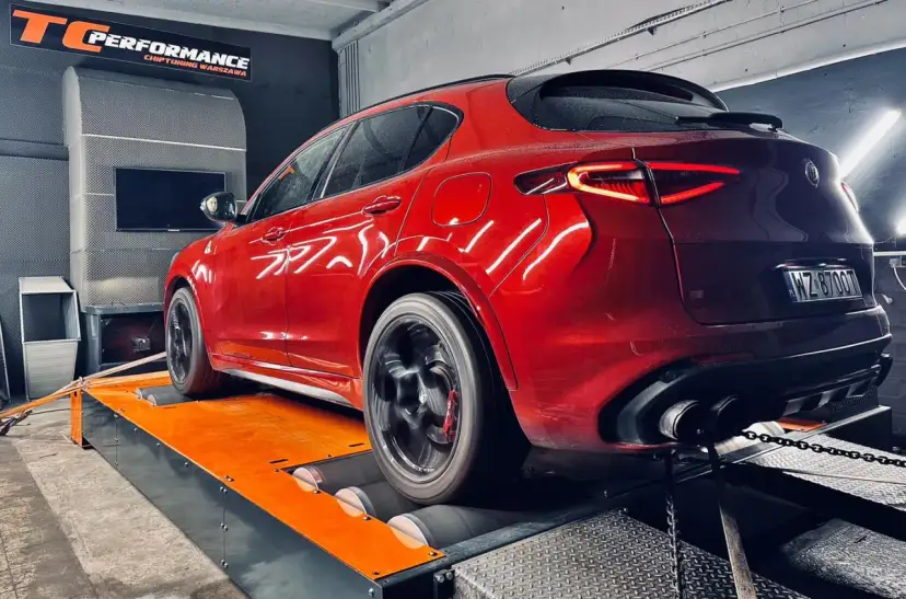 Czerwony SUV na hamowni podwoziowej, testowany w warsztacie.