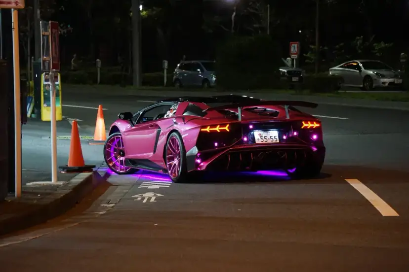 Różowy Lamborghini z neonowym podświetleniem na ulicy nocą.