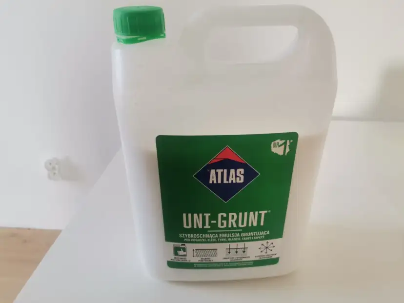 Biały kanister z zieloną nakrętką. Etykieta: "ATLAS UNI-GRUNT SZYBKOSCHNĄCA EMULSJA GRUNTUJĄCA". Dowiedz się, jak stosować ten produkt.