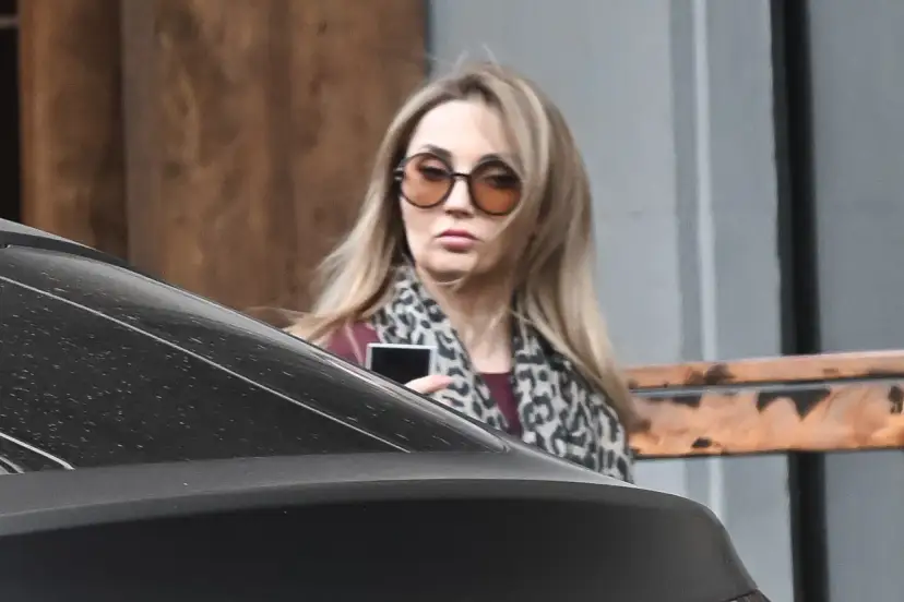 Cleo bez makijażu, w okularach i panterkowej chuście, trzyma telefon.