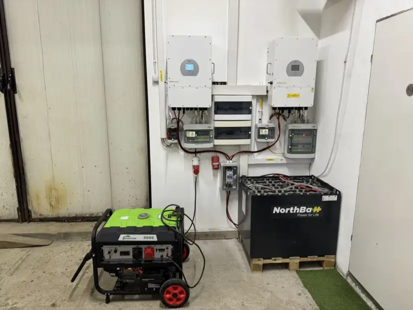 Instalacja fotowoltaiczna z falownikami, akumulatorami i agregatem prądotwórczym. System zapewnia niezawodne zasilanie.