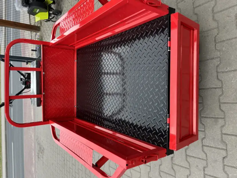 Czerwona przyczepka do glebogryzarki z czarną, antypoślizgową podłogą. Idealna do transportu narzędzi i materiałów. Dowiedz się, jak zrobic przyczepke do glebogryzarki.