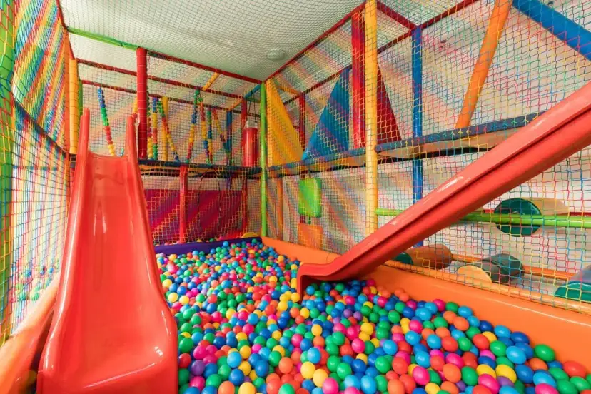 Kolorowy plac zabaw z basenem pełnym piłeczek i zjeżdżalniami.