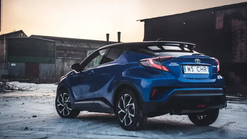 Niebieska Toyota C-HR Hybrid na tle opuszczonych budynków. Czy wybrać hybrydę czy benzynę?