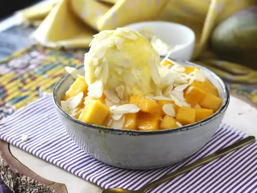 Pyszne Bingsu przepis: mrożony deser z lodami, kostkami mango i płatkami migdałów. Idealny na upalne dni.