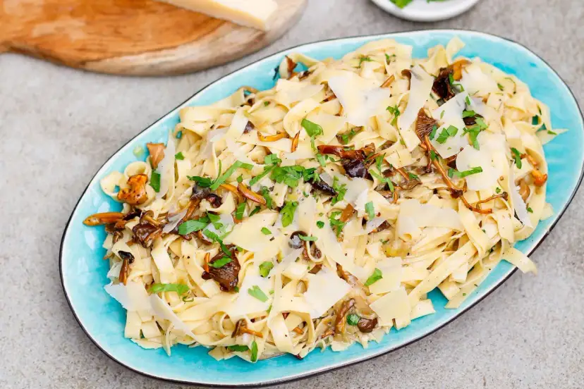 Tagliatelle z grzybami, posypane parmezanem i natką pietruszki. Pyszny przepis na makaron z leśnymi grzybami.