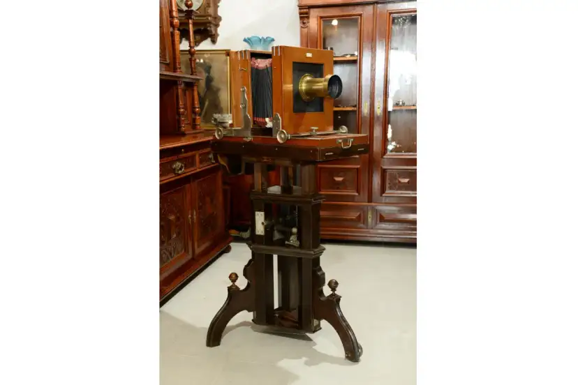 Antyczny aparat fotograficzny na drewnianym statywie z miechem i obiektywem.