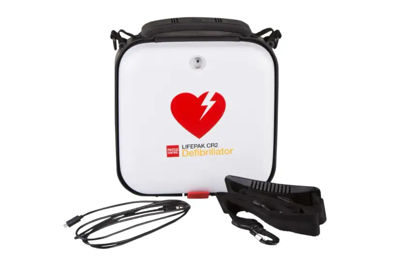 Biały defibrylator LIFEPAK CR2 z czerwonym sercem i piorunem, kablem i paskiem.