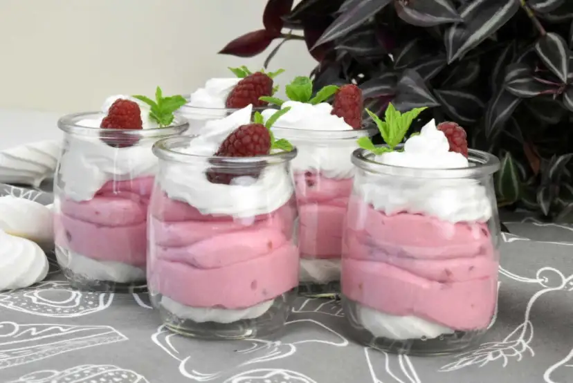 Pyszne desery z mrożonych malin w słoiczkach, udekorowane bitą śmietaną i świeżymi malinami. Idealne na deser!