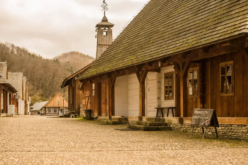 Drewniana zabudowa skansenu, wieża z wiatrowskazem i tablica "Pamiątki Regionalne" - tak z czego słynie Sanok.